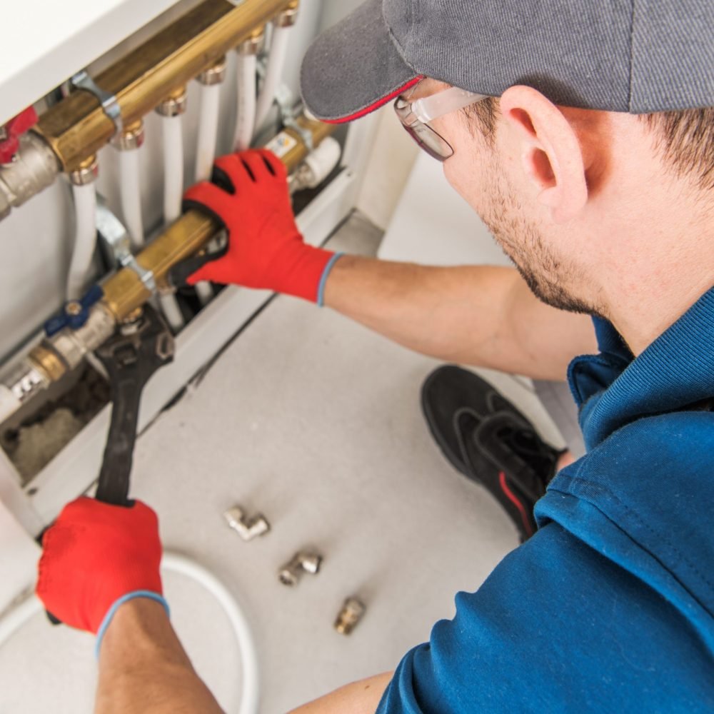 Plumbing System Fix Job. Caucasian Technician Looking For Potential Issue Inside Residential Central Heating System.